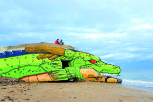 En 2017, Baby K et Blesea réalisent leur rêve d’enfance, en redonnant vie à Shenron du manga Dragon Ball Z, sur la plage de Jonville-Réville. Et ce, sur un bunker échoué, qui a depuis été recouvert par un autre graffiti, la vie banale du Street Art en somme. Les deux compères sont assis sur le dragon maléfique. [©Baby K]
